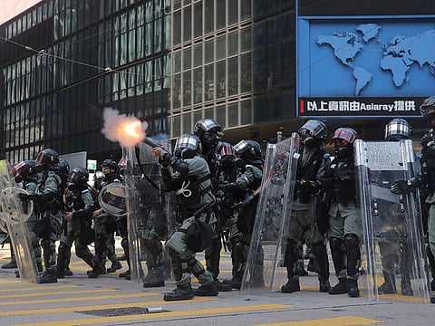 Riot police fire tear gas rounds in the Central district of Hong Kong on Monday, Nov. 11, 2019. A protester was shot by police Monday in a dramatic scene caught on video as demonstrators blocked train lines and roads during the morning commute.