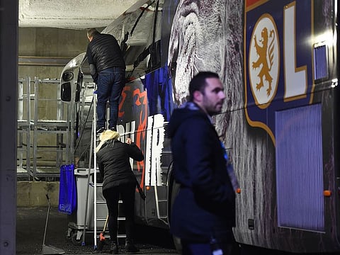 Two people repair a window of Lyon's players bus after it has been broken on their arrival ahead of the against Marseille.