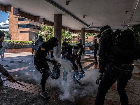 Protesters at Hong Kong Polytechnic University pour water on a tear gas canister on Monday, Nov. 11, 2019.