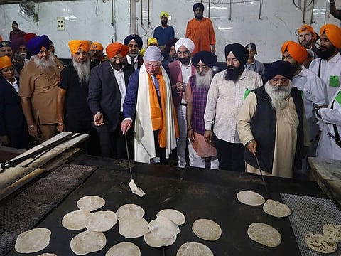 Britain's Prince Charles, center, flips roties or flat Indian bread during his visit to Gurudwara Bangla Sahib, a Sikh Temple in New Delhi, on Wednesday, November 13, 2019.