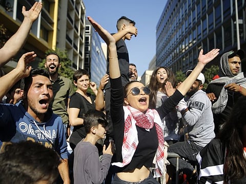 Protesters chant slogans as they block a road leading to the parliament building, in Beirut, Lebanon, Tuesday, Nov. 19, 2019