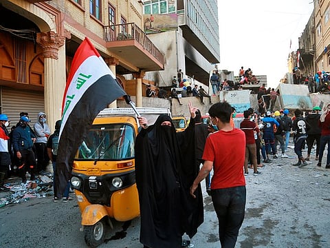 A woman waves the national flag during clashes between security forces and anti-government protesters in Baghdad, Iraq, Sunday, Nov. 24, 2019.