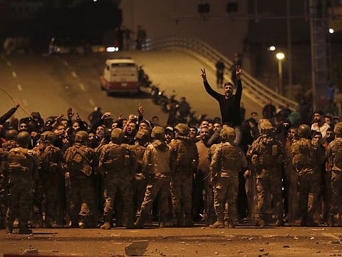 Supporters of the Shiite Hezbollah and Amal Movement groups, shout slogans as they stand in front of Lebanese army soldiers after a clash erupted between the anti-government protesters and them, in Beirut, Lebanon, early Monday, Nov. 25, 2019.