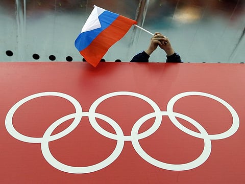 A Russian flag is held above the Olympic Rings at Adler Arena Skating Center during the Winter Olympics in Sochi.