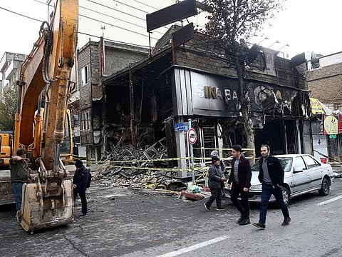 People walk near a burnt bank, after protests against increased fuel prices, in Tehran, Iran November 20, 2019.