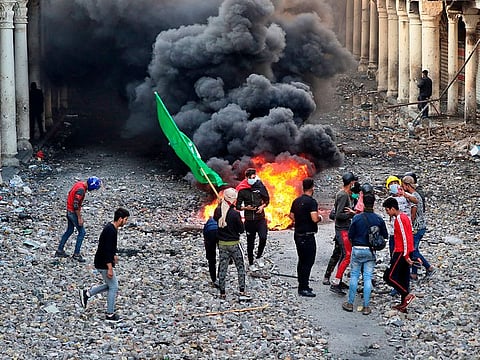 Anti-government protesters set fire while security forces close Rasheed Street during clashes in Baghdad.
