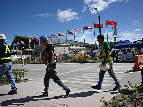 Workers walk past ASEAN members' flags next to the Aquatic centre in New Clark City, in Capas town, Tarlac province north of Manila on November 26, 2019, days ahead of the opening ceremony of SEA Games (Southeast Asian Games).
