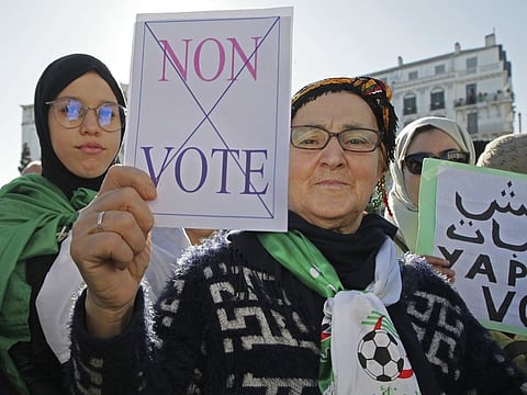 An Algerian demonstrator holds a placard that reads "no vote" as she stage a protest against the government and the upcoming presidential elections in Algiers Friday.