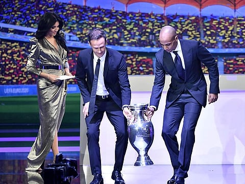 Former Portugal star Ricardo Carvalho (centre), Euro 2020 ambassador, and former Lokomotiv Moscow's Portuguese midfielder Joao Mario bring the winners' trophy on stage next to Romanian TV presenter Corina Caragea during the Euro 2020 finals draw in Bucharest on Sunday.