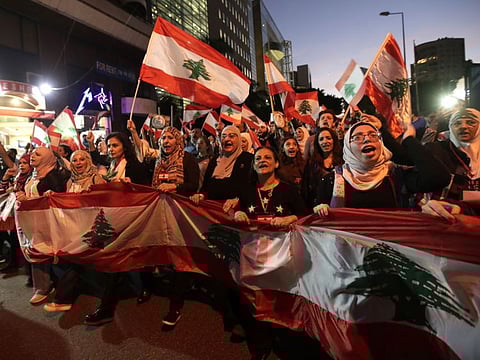 Residents of the Lebanese capital carry national flags as they take part in ongoing anti-government demonstrations in central Beirut on November 30, 2019. More than a month into unprecedented anti-government protests, Lebanon is facing a dual political and economic crisis. / AFP / ANWAR AMRO