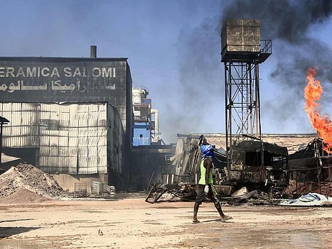Men walk at the scene of a fire at a tile manufacturing unit in an industrial zone in Sudan's north Khartoum, on December 3, 2019.