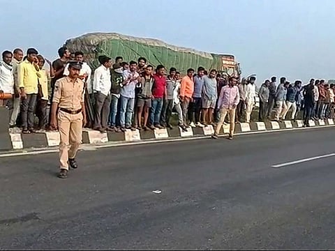People gather at the site of the incident. The accused were killed when they allegedly tried to escape from the crime scene where the police had brought them to re-enact the incident.
