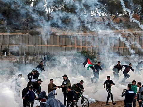 Palestinian protesters run from tear gas fired by Israeli forces amid clashes during a demonstration along the border with Israel, east of Bureij in the central Gaza Strip on December 6, 2019.