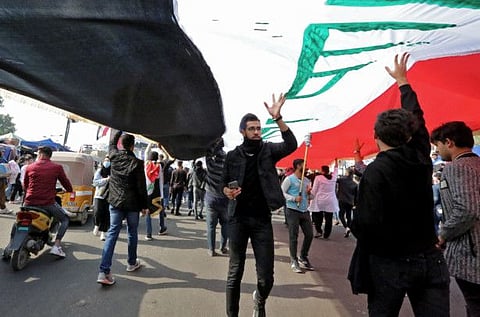 Iraqi demonstrators carry a giant national flag as they rally in Tahrir square in the capital Baghdad on December 8.