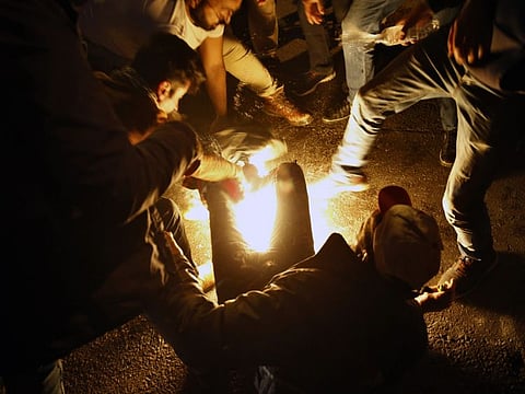 Protesters extinguishing a man who set himself on fire during a women demonstration to protest sexual harassment and bullying and demanding rights, in front of the government house in downtown Beirut, Lebanon, Saturday, Dec. 7, 2019.