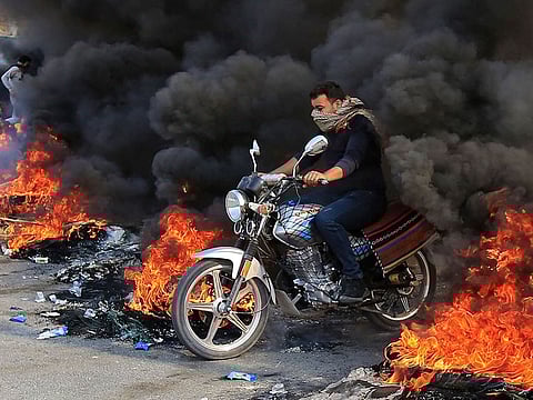 An Iraqi man drives through burning tyres in the city of Karbala, south of Iraq's capital Baghdad, on November 26, 2019.