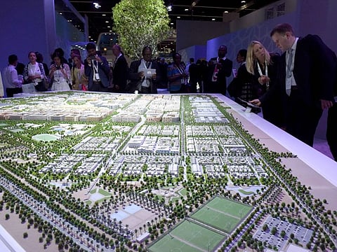 Visitors look at the model of Masdar City at the opening of Abu Dhabi Sustainability Week