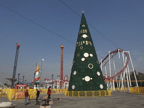 In this Thursday, Dec. 5, 2019 photo, people walk near a large Christmas tree in al-Zawra Park, Baghdad, Iraq.