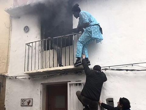 Neighbours save a man from a burning apartment in Denia, Spain December 6, 2019 in this picture obtained from social media.