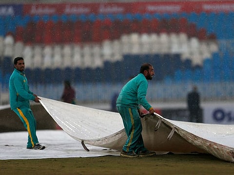 Groundsmen pull the covers on in Rawalpindi.