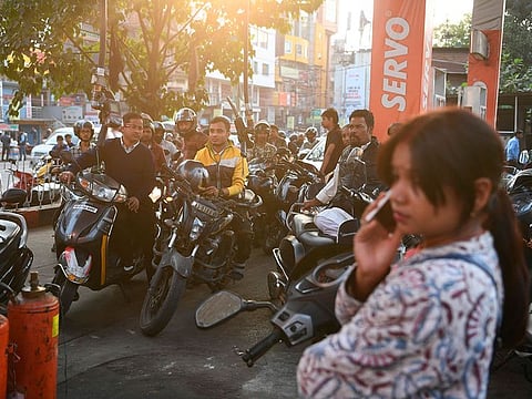 Residents waits to get petrol from a petrol pump in Guwahati on December 14, 2019.