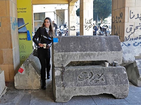 People walk through concrete barricades that were erected overnight to block or control access to protest sites, following attacks by counter-demonstrators, in the capital Beirut on December 18, 2019.