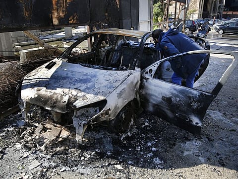 A man looks at a burned car that was set on fire early Tuesday by supporters of the Shiite Hezbollah and Amal Movement groups, in Beirut, Lebanon, Tuesday, Dec. 17, 2019. Supporters of Lebanon's two main Shiite groups Hezbollah and Amal clashed with security forces and set fires to cars in the capital early Tuesday, apparently angered by a video circulating online that showed a man insulting Shiite figures.(AP Photo/Hussein Malla)