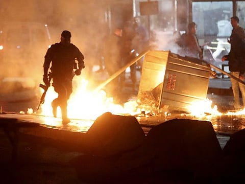 A Lebanese army soldier, runs next of garbage containers that set on fire to block the roads by the supporters of the outgoing Prime minister Saad Hariri, as they protest to reject the newly-assigned Lebanese Prime Minister, Hassan Diab, in Beirut, Lebanon, Thursday, Dec. 19, 2019.