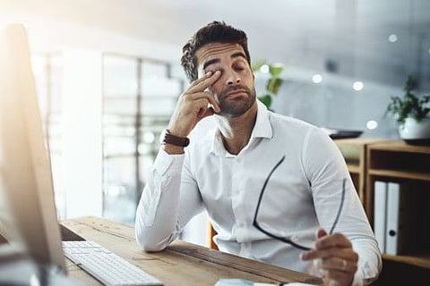 Shot of a young businessman looking stressed out and tired while working in an office