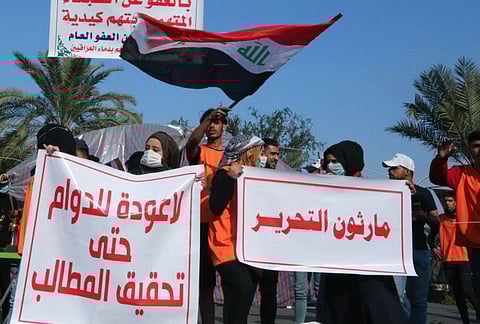 Iraqi students carry banners as they march during ongoing anti-government demonstrations in the capital Baghdad's Tahrir square, on December 22, 2019.