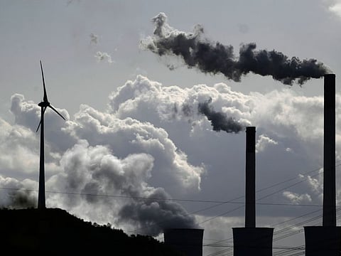 Steam rises from a coal power plant of global energy supply company Uniper beside a wind turbine in Gelsenkirchen, western Germany, on October 02, 2019.