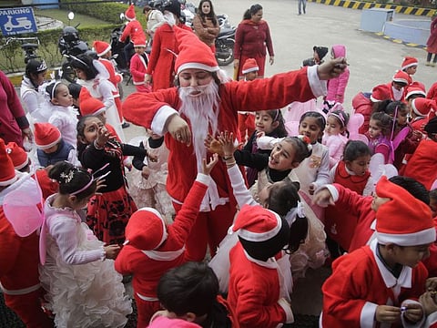 A teacher dressed as Santa Claus distributes candies among the children as they celebrate Christmas at their school, in India