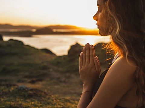 Woman praying alone at sunrise. Nature background. Spiritual and emotional concept. Sensitivity to nature