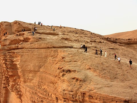 Tourists, led by Ghazi Al-Anazi, climb a rock formation in the desert near Riyadh, Saudi Arabia.