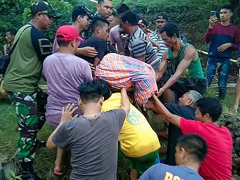 This handout picture taken and released on December 26, 2019 by Kendari Search and Rescue Agency shows villagers and a rescue team moving a victim's body after being killed by a crocodile near Bendewuta village, North Konawe, in Indonesia's Southeast Sulawesi.