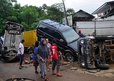 This picture taken on January 2, 2020 shows residents walking past destroyed cars in Bekasi, West Java, after flooding triggered by heavy rain hit the area.
