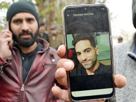 A friend of the victim Parvinder Singh shows his photo on his phone while his brother Harmeet Singh can also been seen in Peshawar on Sunday