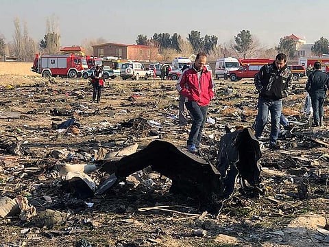People walk near the wreckage after a Ukrainian plane crashed near Imam Khomeini airport in Tehran