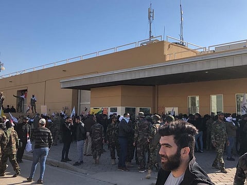 Dozens of Iraqi Shiite militia supporters outside the US embassy compound in Baghdad, Iraq, Tuesday, Dec. 31, 2019. An angry mob smashed a door and stormed inside the compound following deadly US military airstrikes against the Kataeb Hezbollah militia in Iraq and Syria
