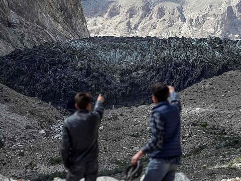 This picture taken on June 28, 2019 shows men pointing at the black Shisper glacier in the Karakoram mountain range of Pakistan's Gilgit-Baltistan region.