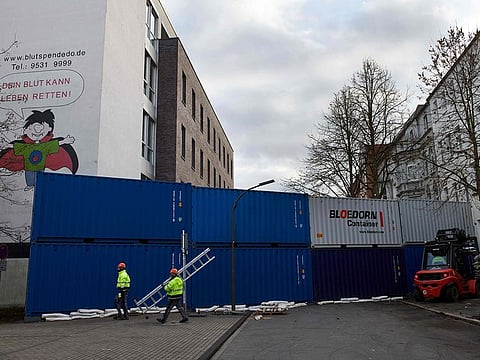 A wall made up of containers is erected by workers to protect the houses in a street where World War II bombs were discovered in Dortmund, western Germany on January 11, 2020.