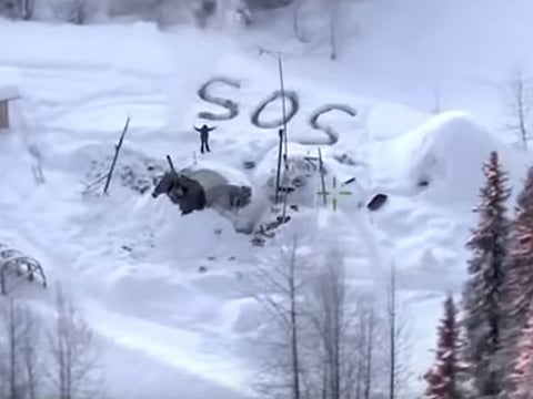 In this image made from video released by the Alaska State Troopers, an aerial helicopter view from January 9, 2020, shows a man waving with distress signal "S.O.S." outside Susitna Valley, Alaska. Alaska State Troopers rescued Tyson Steele, 30, who survived in a makeshift shelter after his remote cabin burned last month.