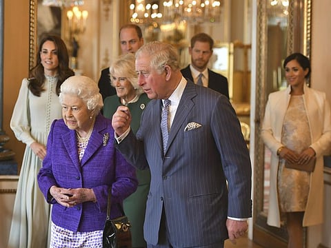 Britain's Queen Elizabeth II is joined by Prince Charles, the Prince of Wales, and at rear, from left, Kate, Duchess of Cambridge, Camilla, Duchess of Cornwall, Prince William, Prince Harry and Meghan, Duchess of Sussex during a reception at Buckingham Palace, London, Tuesday March 5, 2019, to mark the fiftieth anniversary of the investiture of the Prince of Wales. (Dominic Lipinski/Pool via AP)