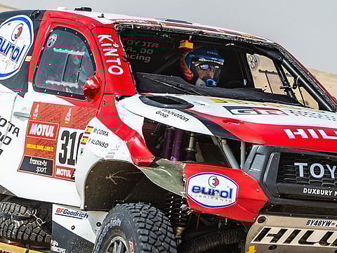 Fernando Alonso races through the dunes after losing his windscreen while rolling his Toyota.