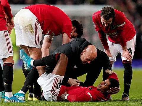 Manchester United's Marcus Rashford receives medical attention after sustaining an injury.