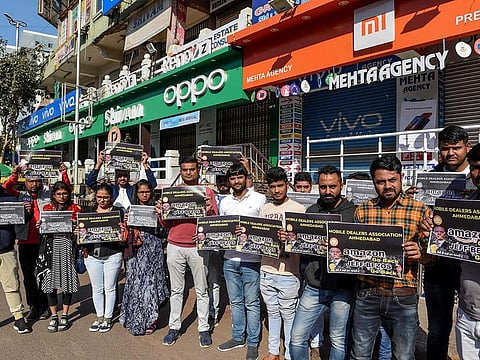 Mobile dealers and members of Ahmedabad Mobile Dealer's Association hold placards as they protest against online shopping platform Amazon outside their closed mobile shops in Ahmedabad on January 15, 2020. Amazon tycoon Jeff Bezos has promised a new billion-dollar investment in India, just two days after authorities launched an anti-trust investigation into the e-commerce giant.