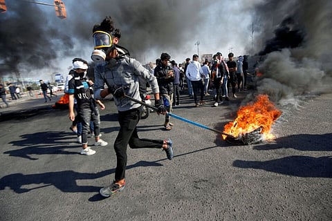 An Iraqi demonstrator pulls a burning tire during ongoing anti-government protests in Basra, Iraq January 20, 2020.