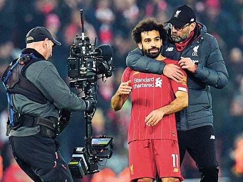 A cameraman films Liverpool manager Jurgen Klopp embracing his team's Egyptian midfielder Mohammed Salah after a crucial win against Manchester United at Anfield on Sunday night.