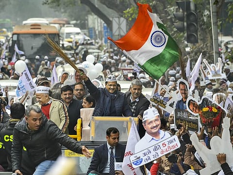 AAP convenor and Delhi Chief Minister Arvind Kejriwal waves a broom, the party symbol, during a roadshow in New Delhi on Monday.