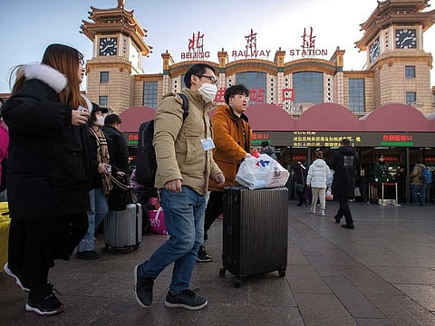 A traveler wears a face mask as he walks outside of the Beijing Railway Station in Beijing